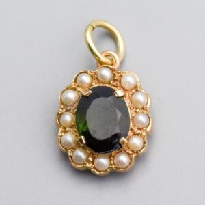 Solid 9K Gold Antique Green Tourmaline and Pearl Pendant   This 9K gold antique pendant showcases a striking oval-cut green tourmaline at its centre, surrounded by a halo of 12 delicate seed pearls.