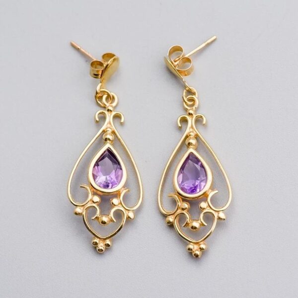 Solid 9K Gold Amethyst Drop Earrings  This pair of 9K gold amethyst drop earrings features a pear-cut amethyst at its centre, elegantly set in a polished gold bezel.   Surrounding the gemstone is intr